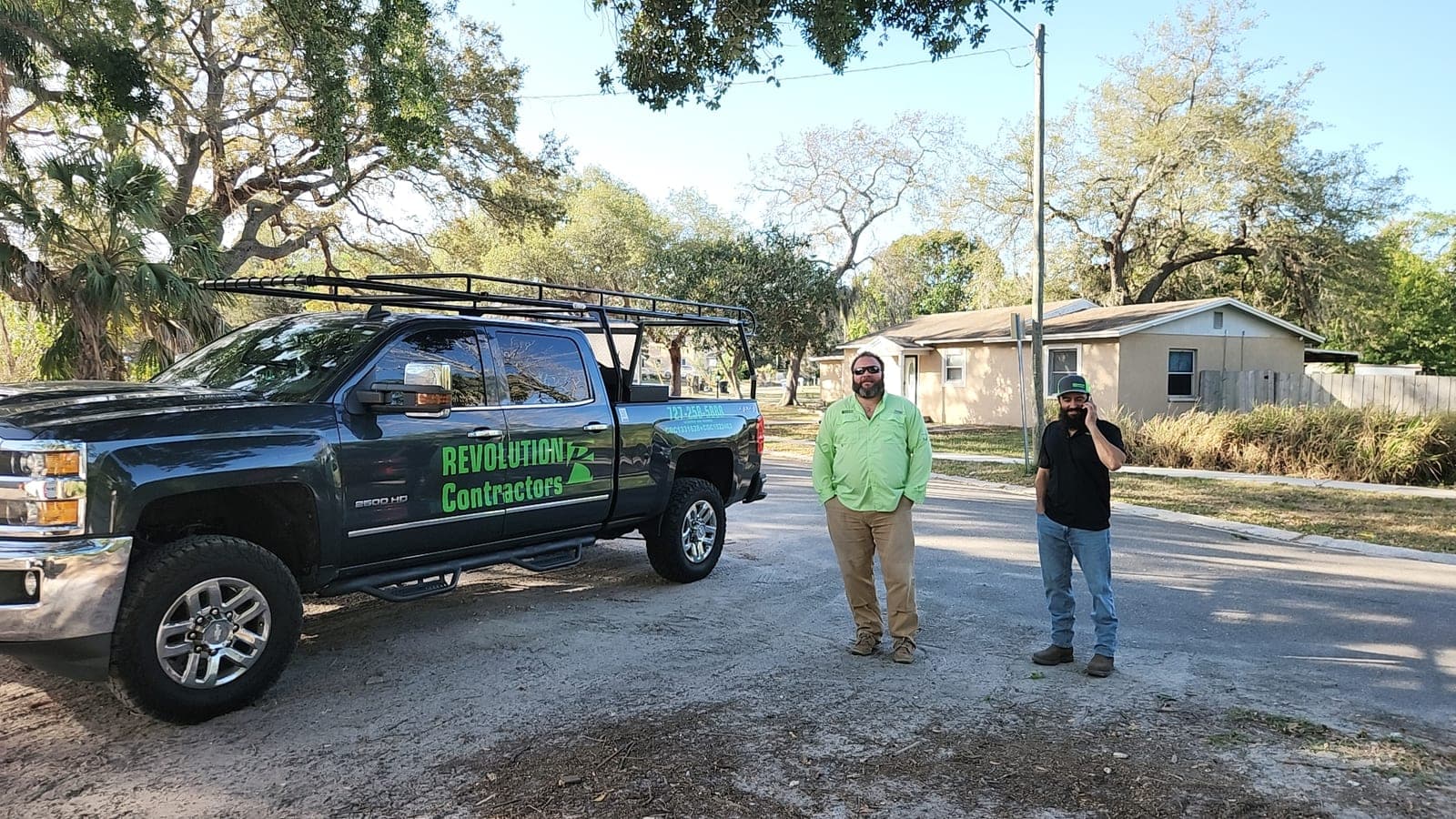 Revolution Contractors truck at a St. Petersburg worksite with two crew members standing beside it