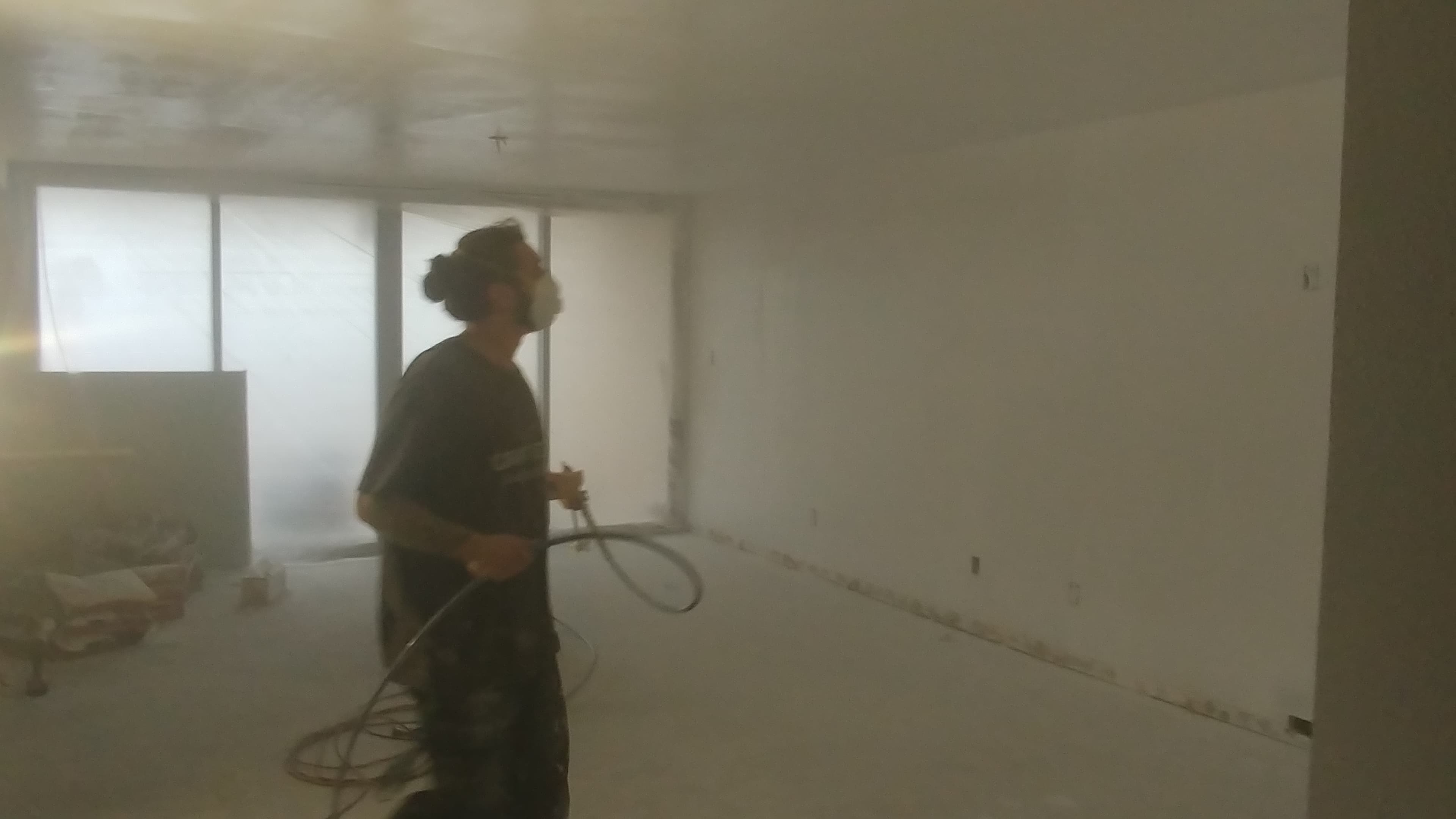 Contractors On Call painter in respirator running an airless sprayer during a St. Petersburg interior repaint